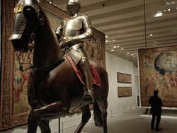 Someone in armour on a model horse in a gallery