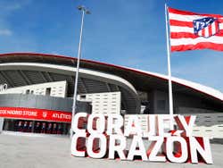 A sign outside of the Wanda Metropolitano Stadium with the Atletico flag flying against a bright blue sky