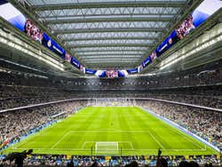 A large football stadium with a covered roof and stands full of spectators